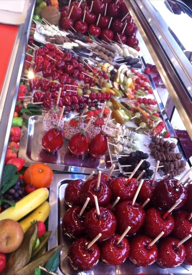 Glasierte Äpfel und Erdbeeren am Spieß, rot glänzend in der Vitrine