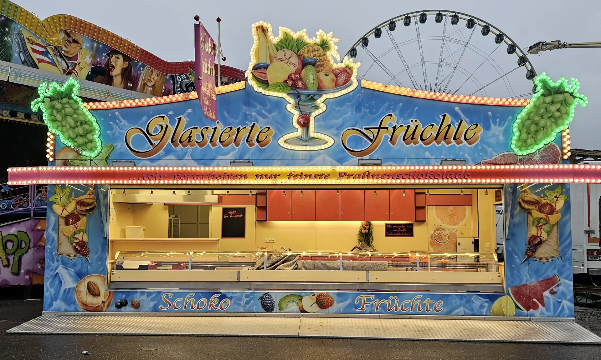 Der himmelblaue Wagen Glasierte Früchte mit goldener Schrift, dahinter ein Riesenrad