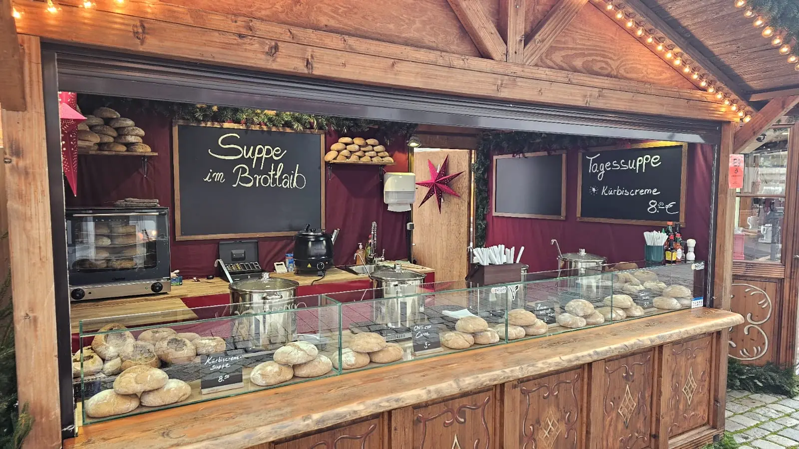 Der Stand mit Suppe im Brotlaib am Abend, Holzhütte mit Lichterkette