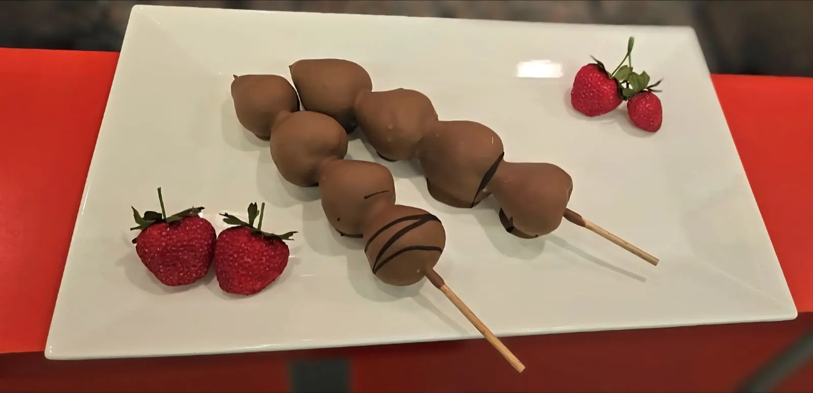 Schokofrüchte am Spieß mit frischen Erdbeeren auf einem weißen Teller