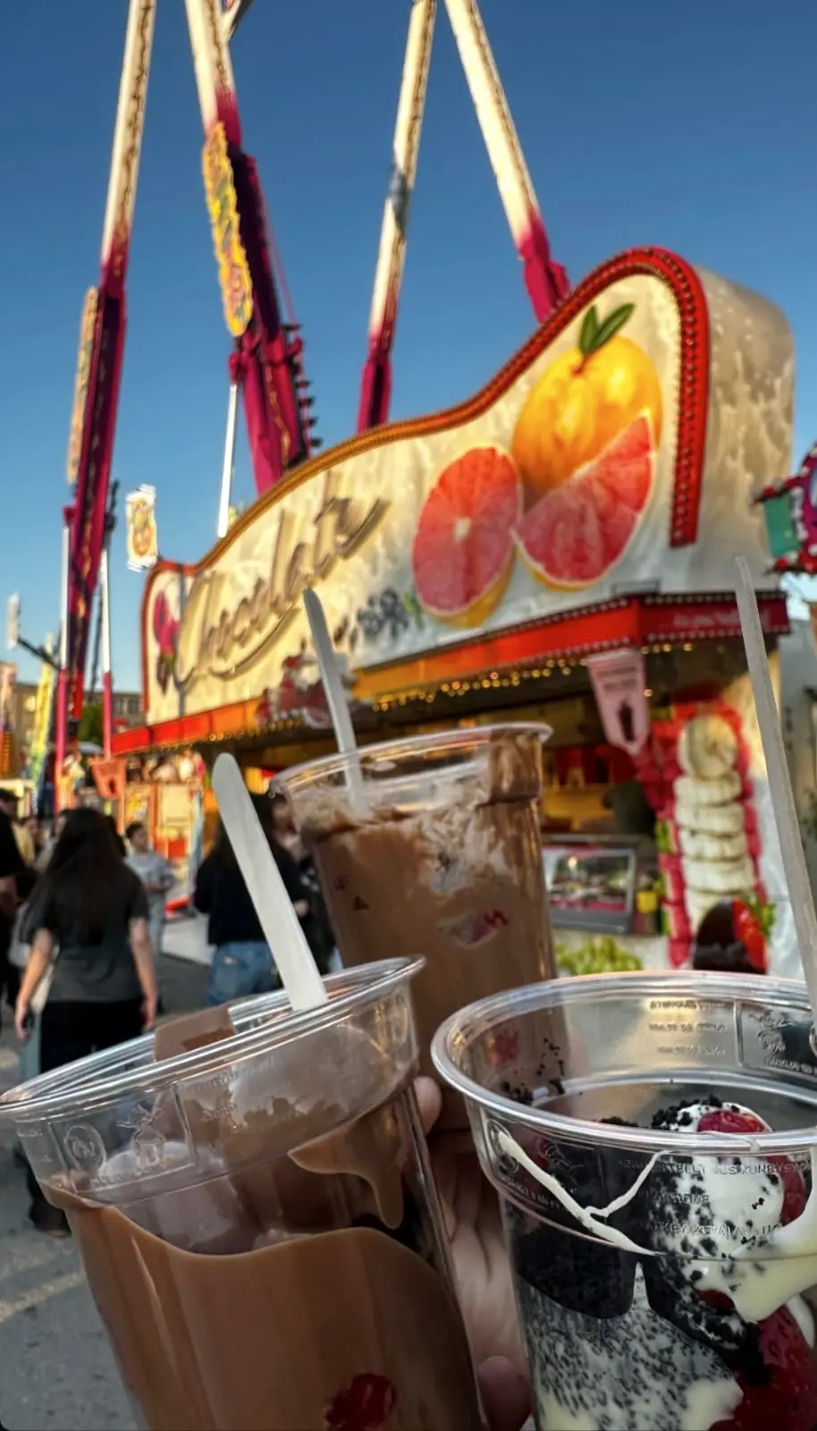 Zwei Becher mit Schokolade und Früchten vor dem Wagen auf dem Festplatz
